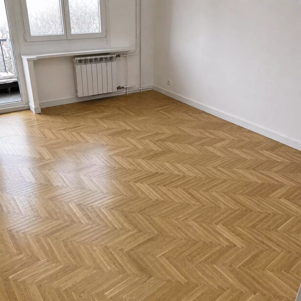 La même pièce après ponçage, parquet en chevrons clair et uniforme