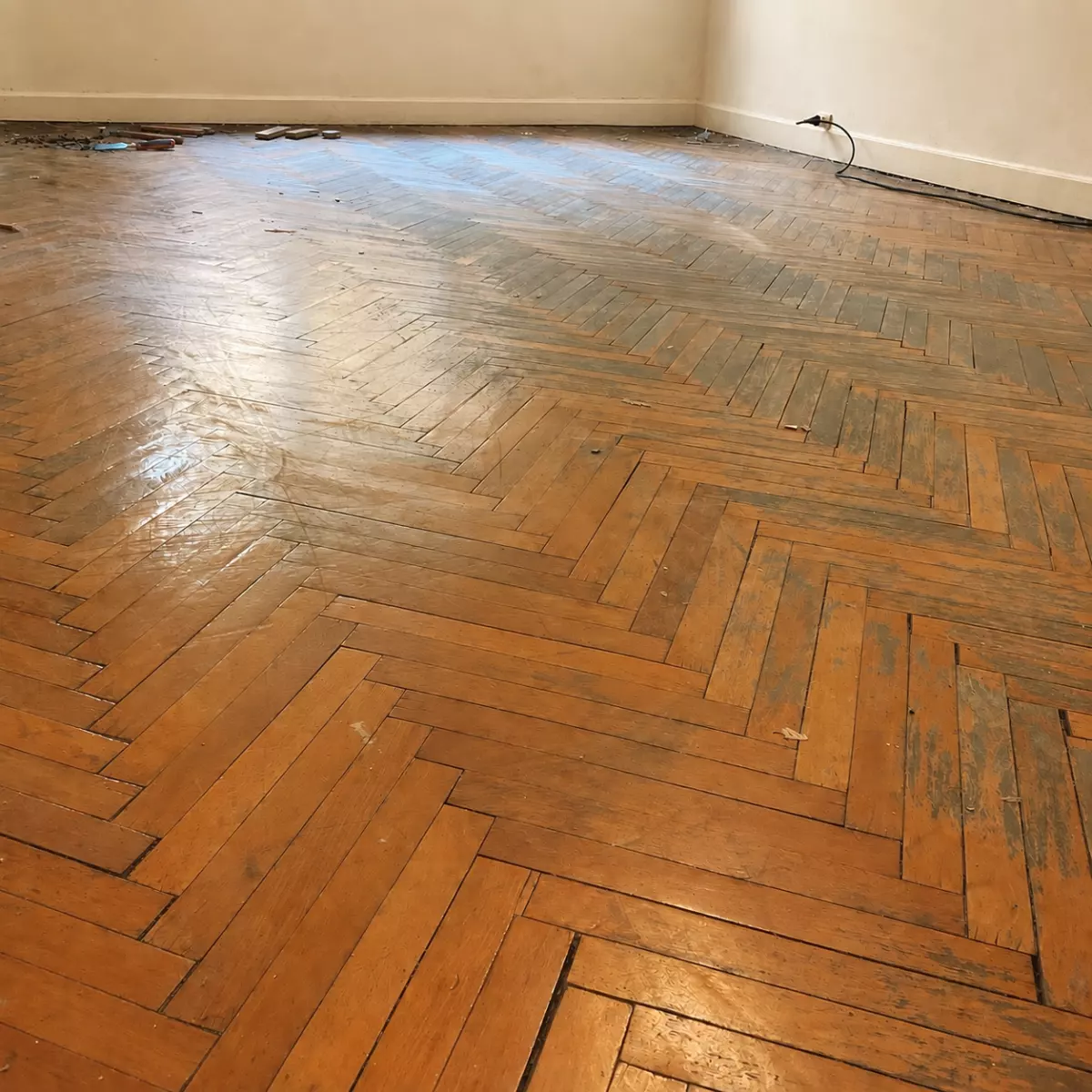 Parquet en chevrons avant ponçage, ancienne finition usée et irrégulière